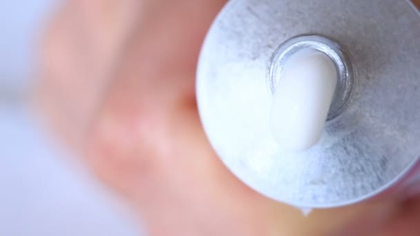 Crema blanca hidratante exprimida de un tubo sobre un fondo blanco
 - Imágenes, Vídeo