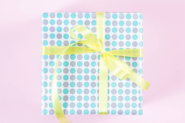 Geschenkbox mit gelbem Band auf rosa Hintergrund - Foto, Bild