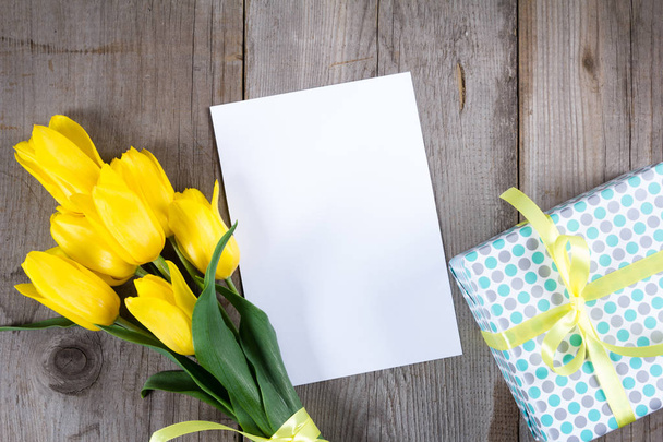 Ramo de tulipanes amarillos y caja de regalo sobre fondo de madera gris
 - Foto, imagen