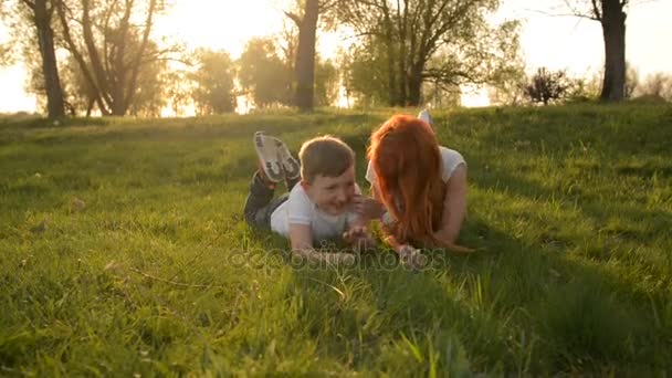 Madre e hijo divirtiéndose al aire libre acostados en la hierba
 - Metraje, vídeo