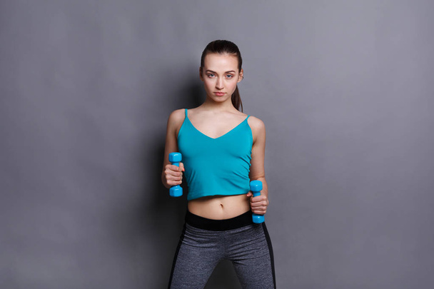Fitness model woman with dumbbells at studio background - Foto, afbeelding