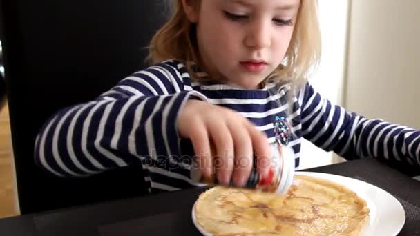 Menina em vestido listrado sentado em uma mesa, comer panquecas com mousse de maçã ou geléia e canela
 - Filmagem, Vídeo