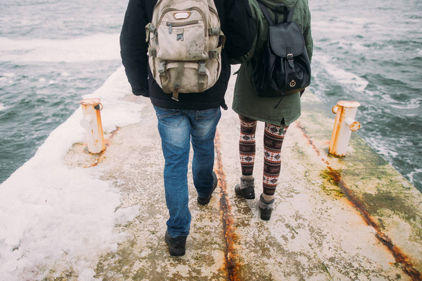 Happy stylish couple walking on the old pier in winter vacation. Travel together concept. Sea background - Foto, imagen