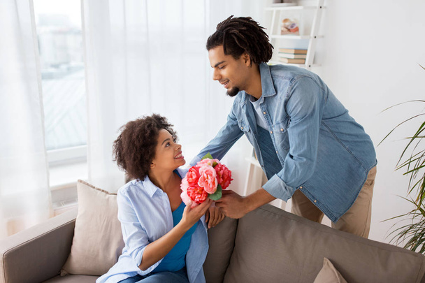 happy couple with bunch of flowers at home - Photo, Image