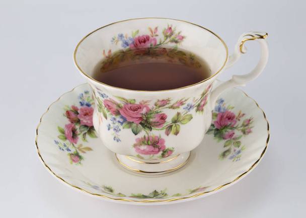 Chávena de chá e pires antigos com decoração rosa e dourada
  - Foto, Imagem