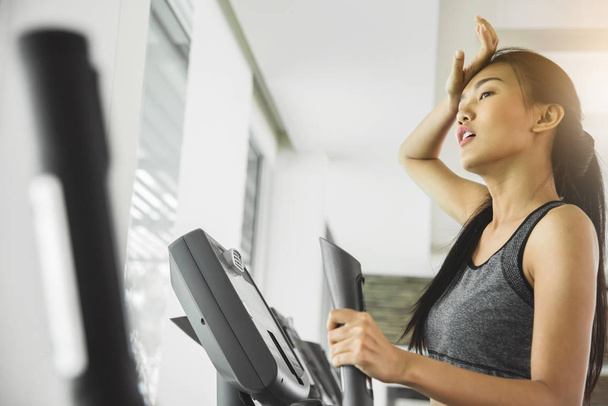 Asian woman with sweat exercising on Elliptical trainer machine  - Фото, зображення