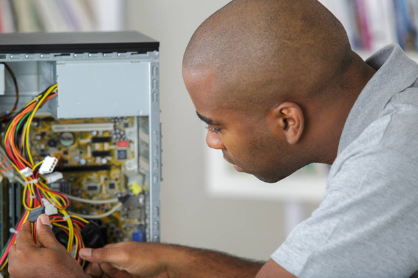 Man working on wiring of computer - Фото, изображение