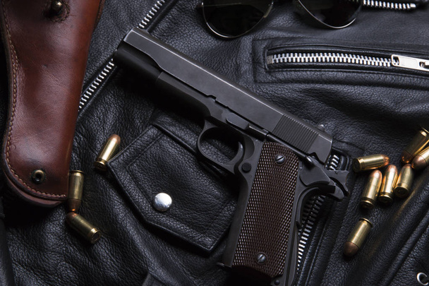 Colt pistolet avec balles et étui repose sur une veste en cuir
 - Photo, image