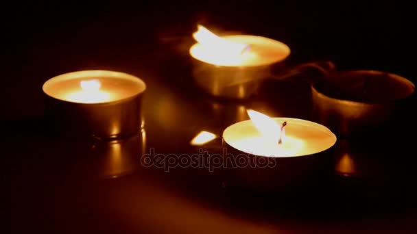 Primer plano del viento apagando las velas ardientes en la mesa de madera marrón oscuro
 - Imágenes, Vídeo