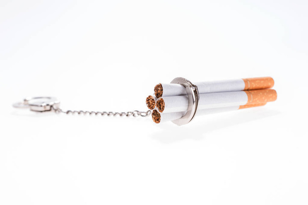 Addition concept with cigarettes and handcuffs on white - Photo, Image