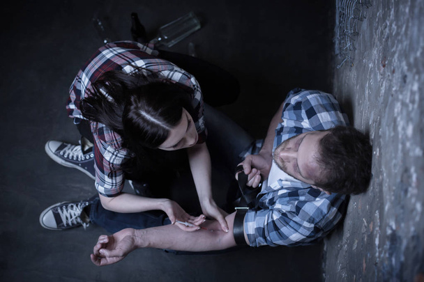 Helpful addicts making heroin injection in the dark place - 写真・画像
