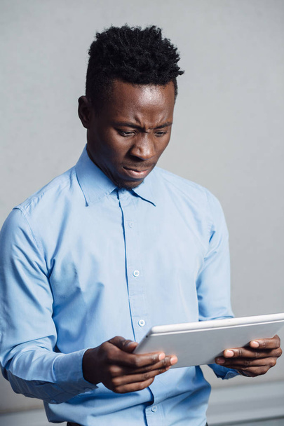 African man embarrassed looking to screen of the tablet PC - Photo, image