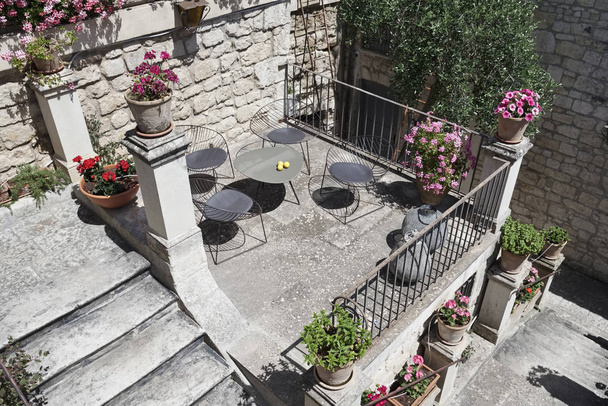 Italia, Sicilia, Modica (provincia de Ragusa), sillas en una terraza con flores
 - Foto, Imagen