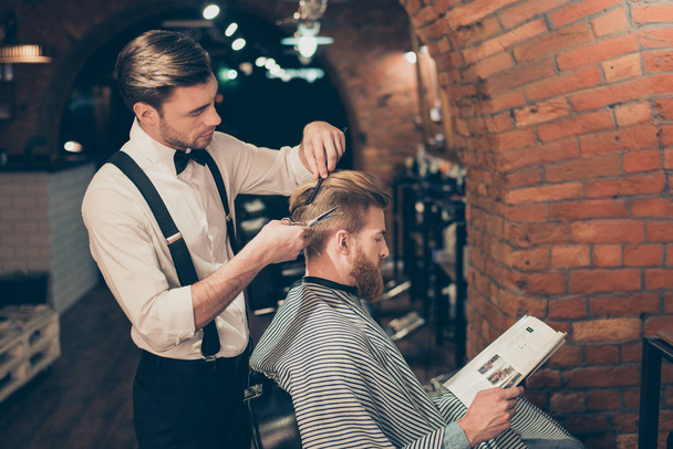 Red bearded guy is reading a magazine in a barber shop while get - Photo, image