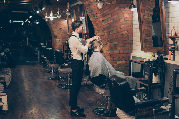 Barber shop classy dressed specialist is styling the hair of a c - 写真・画像