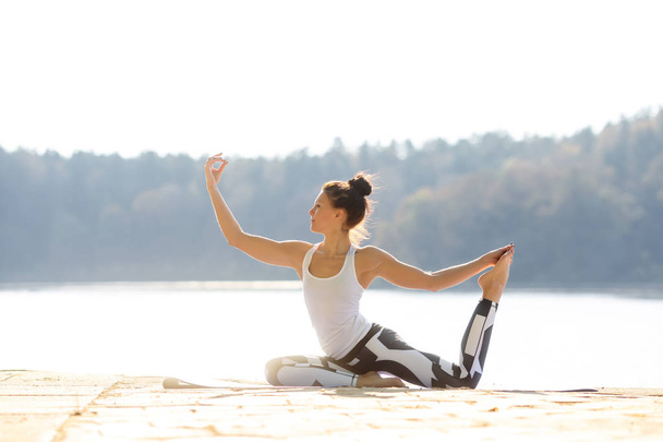 Genç kadın yakın göl açık havada, meditasyon Yoga yapıyor. Spor fitness ve doğada egzersiz. Sonbahar günbatımı. - Fotoğraf, Görsel