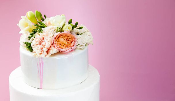 Элегантный свадебный многоуровневый торт, украшенный свежими розами и фризией
 - Фото, изображение