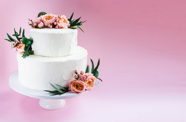 Elegant wedding tiered cake decorated with fresh roses and freesia - Фото, зображення