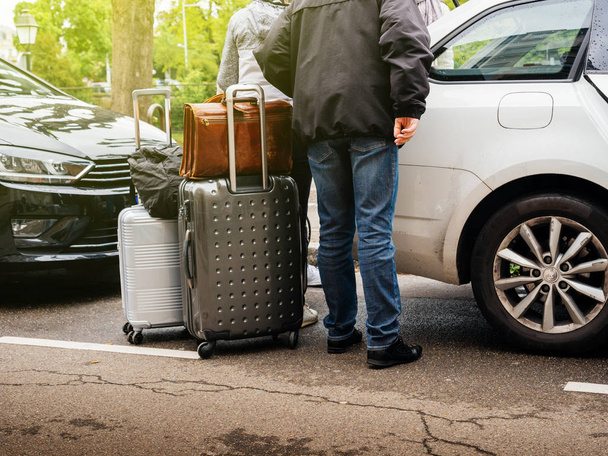 Personas que agregan equipaje múltiple en la ciudad estacionada en el maletero
  - Foto, Imagen