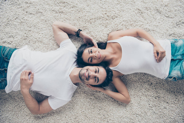 Charming couple of young beautiful lovers are lying on the beige - Fotó, kép