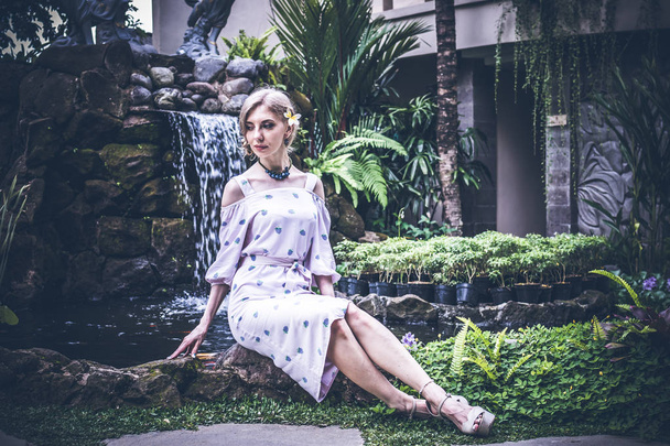 Donna sta posando in un giardino tropicale dell'isola di Bali, Indonesia. Cascata di giardino su uno sfondo. Sexy giovane donna
. - Foto, immagini