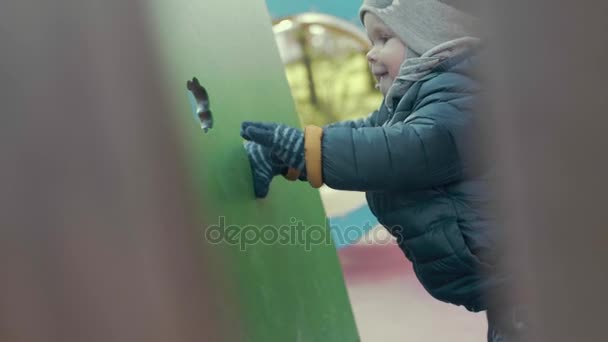 MOCIÓN LENTA Lindo niño europeo poco activo jugando en el patio de recreo en tiempo fresco
 - Metraje, vídeo