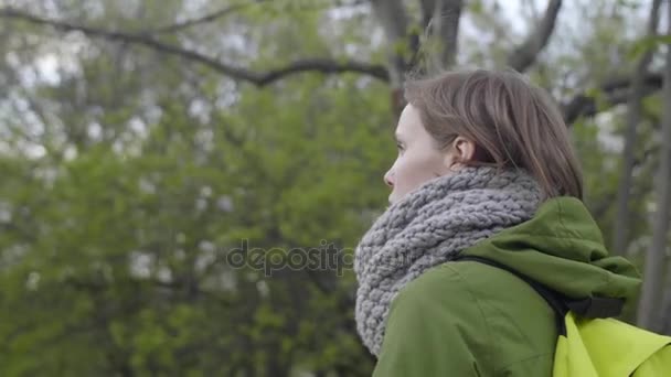 Όμορφη Ευρωπαϊκή έφηβος κορίτσι με ένα σακίδιο και ένα ζεστό κασκόλ απολαμβάνοντας βόλτα στο πάρκο, αργή κίνηση - Πλάνα, βίντεο