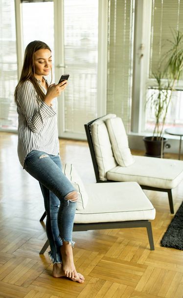 Young woman with phone in the room - Foto, Bild