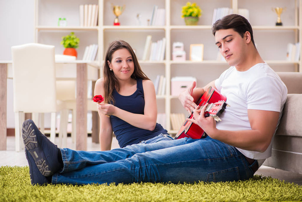 ロマンチックなペアは床にギターを演奏 - 写真・画像