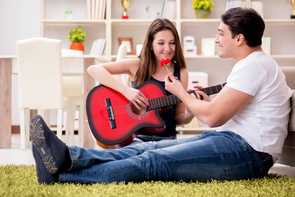 Романтична пара грає на гітарі на підлозі
 - Фото, зображення