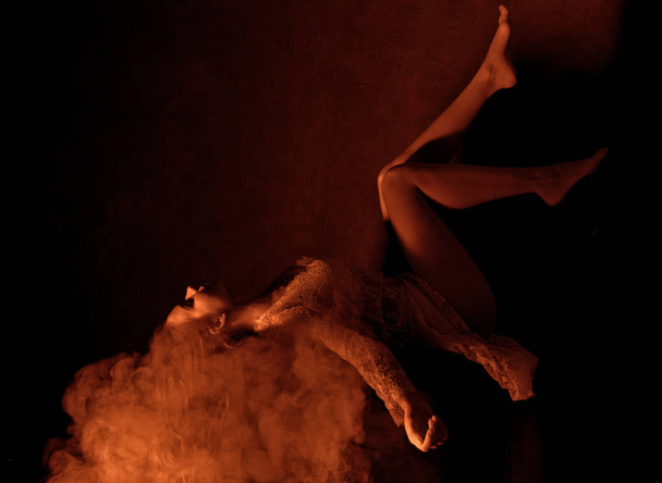 beautiful woman lies in a flame smoke on a dark background - Foto, Imagem