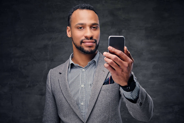 Αμερικανική αρσενικό σε ένα γκρι κοστούμι κατέχει το smartphone - Φωτογραφία, εικόνα