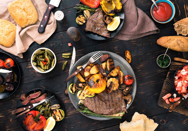grilled steak and grilled vegetables on dark wooden table - Photo, image