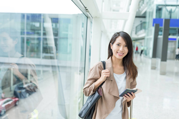 Mulher segurando celular e passaporte no aeroporto
 - Foto, Imagem