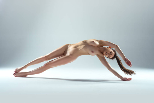 Beautiful Naked Woman Levitating Isolated On The Gray Background - Foto, Imagem
