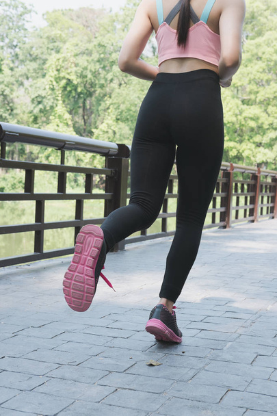 Female sport fitness runner jogging outdoors on bridge in spring - Фото, изображение