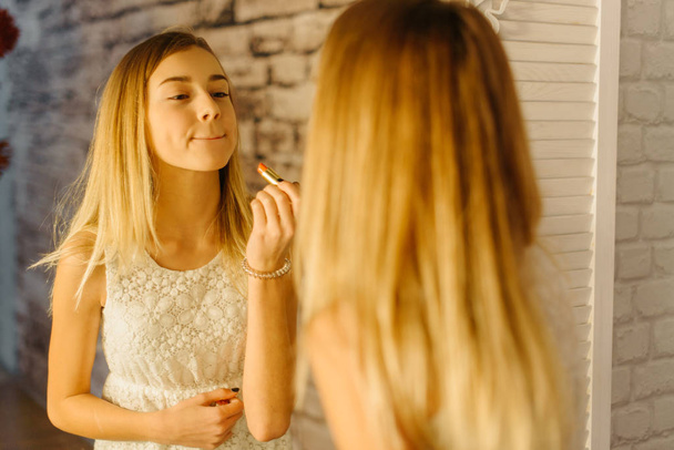 The reflection of the young girl applying the lips. - Φωτογραφία, εικόνα