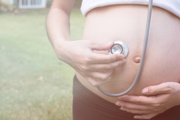 asian pregnant woman using stethoscope to hear her baby heart to - Photo, Image