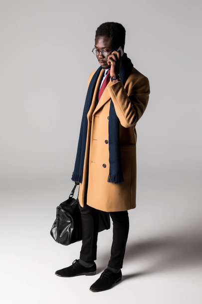 Portrait latéral complet de jeune homme d'affaires africain utilisant un téléphone portable isolé
 - Photo, image