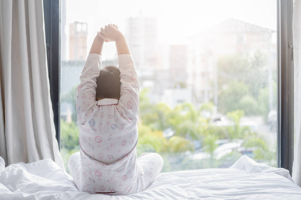 obez şişman çocuk pijamaları yatağın üstüne oturuyor - Fotoğraf, Görsel