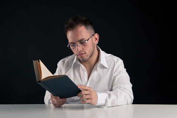 Young man reading a book against black background - 写真・画像