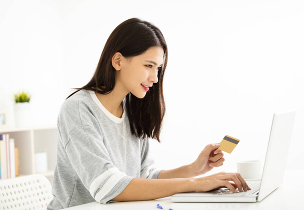 mujer joven con tarjeta de crédito y mirando a la computadora portátil
 - Foto, Imagen