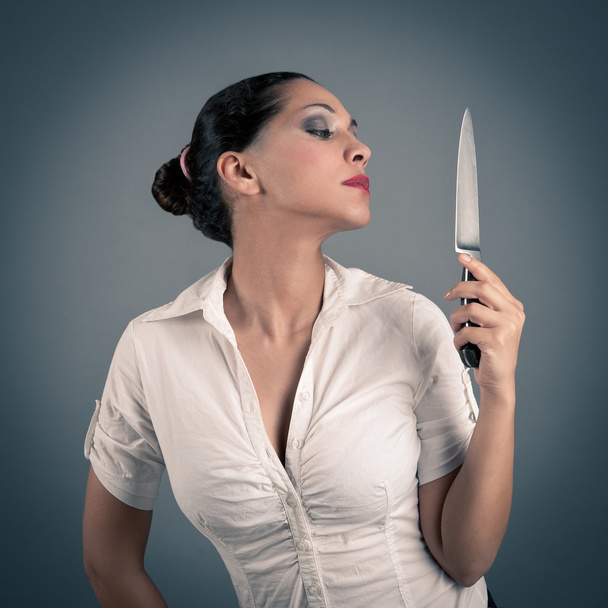 Sexy brunette woman holding a knife against dark background - Fotoğraf, Görsel