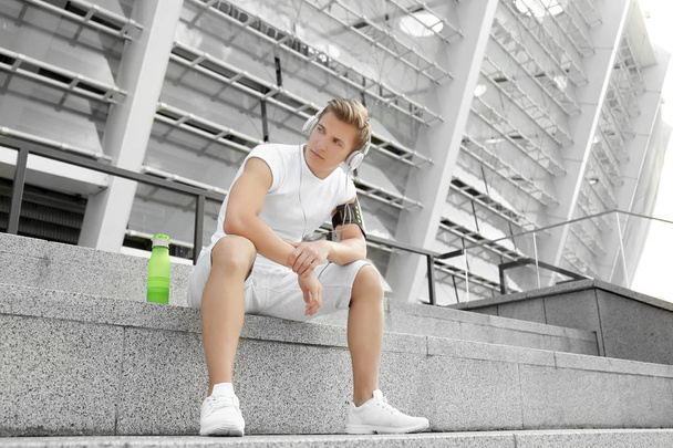Young man with headphones sitting on  stairs - Photo, image