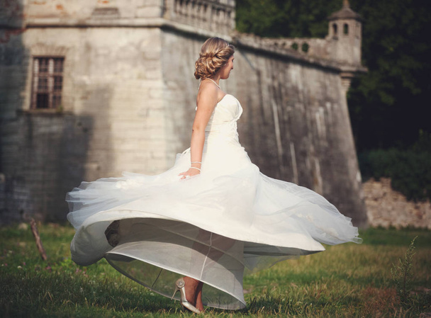 Classy bride whirls behind an old castle - Fotó, kép