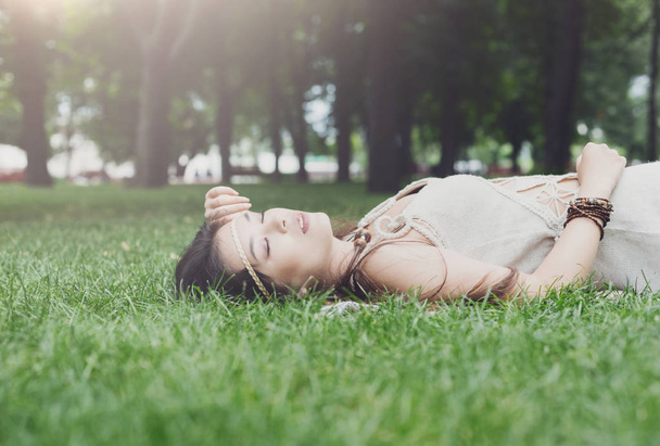 Beautiful young girl lying on grass in summer park - Fotó, kép