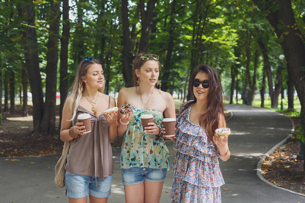 Trzy piękne młode boho chic stylowe dziewczyny spaceru w parku. - Zdjęcie, obraz