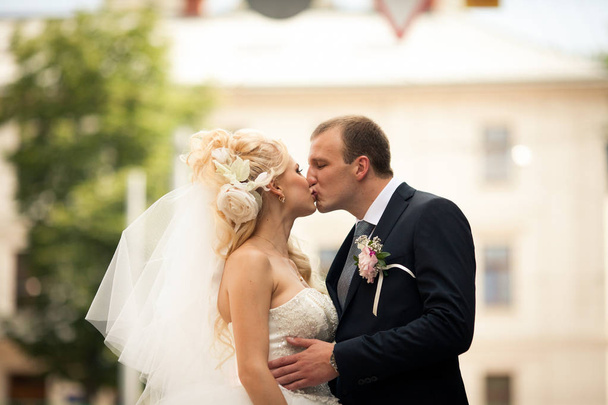 Groom kisses bride hugging her delicate waist - Фото, зображення