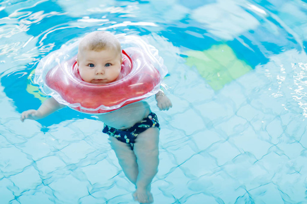 Słodkie małe dziecko nauki pływania z pierścieniem kąpieli w krytym basenem - Zdjęcie, obraz