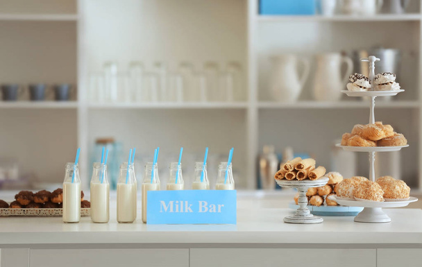 Bottles, desserts and card with text MILK BAR  - Фото, изображение